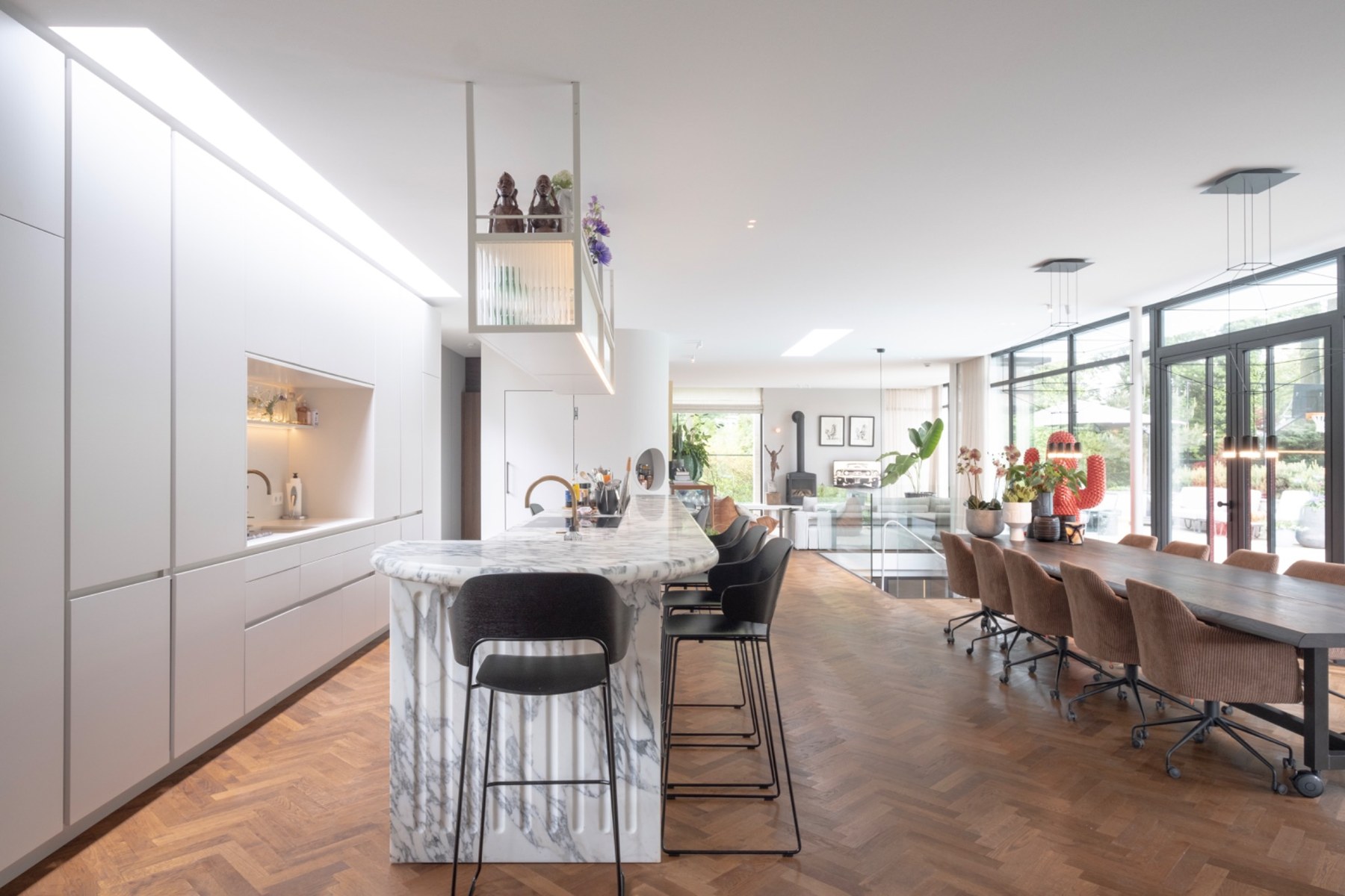 Lichte woonkeuken met marmeren eiland en lange eettafel